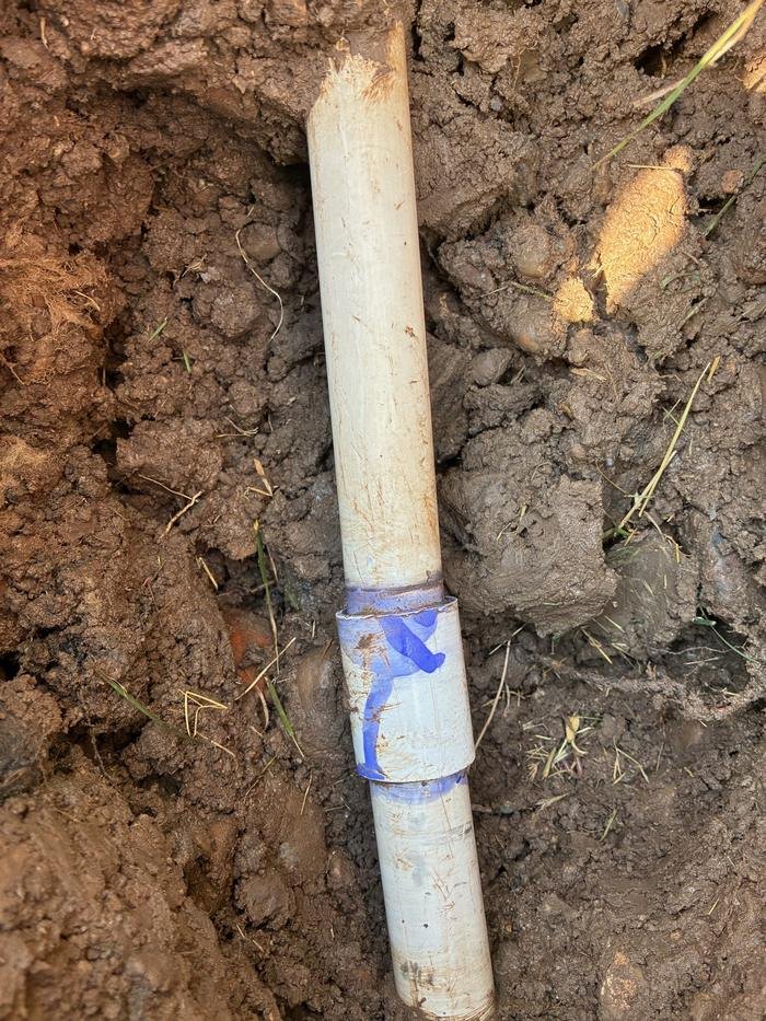 White PVC sprinkler pipe with blue tape wrapped around a failed joint.